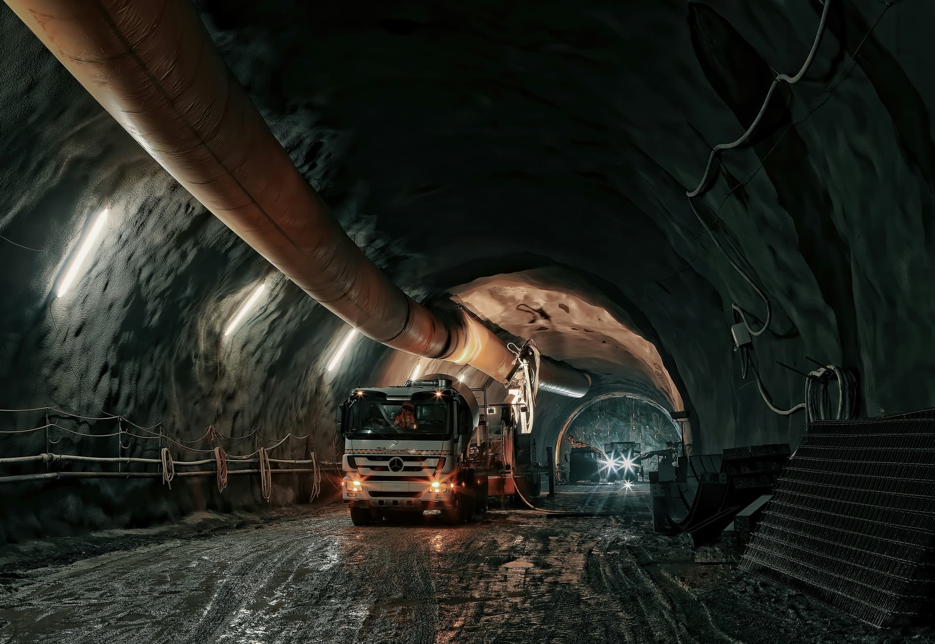 Underground tunnel with ventilation duct and mining vehicle